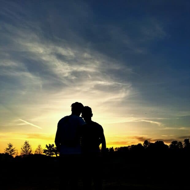 Silhouette of two people leaning together at sunset.