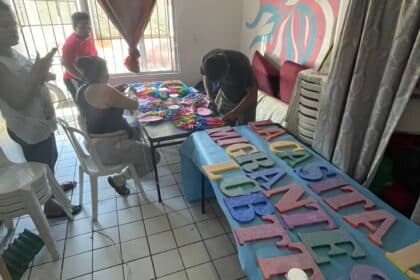People crafting colorful letters at a table.