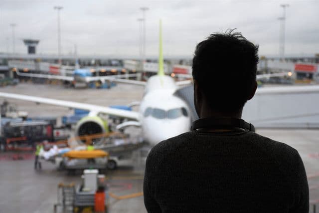 Person viewing an airplane through an airport window.