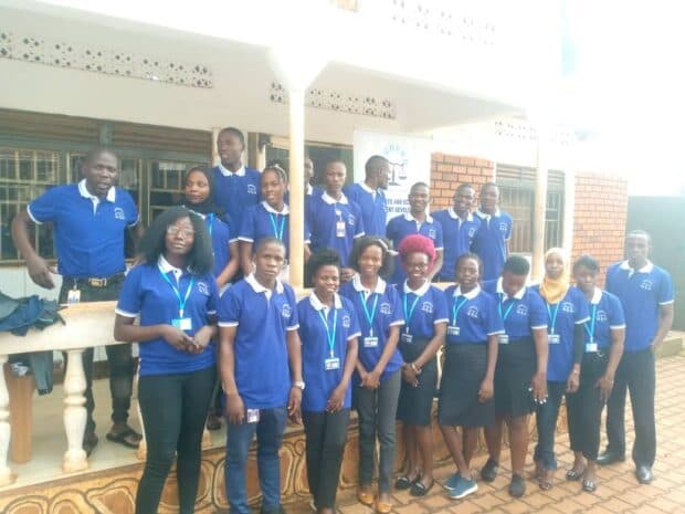 Group of people in matching blue shirts posing outside a building.