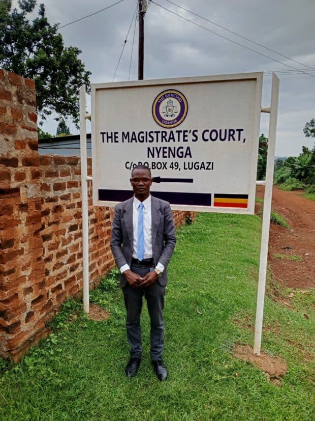 Person in a suit standing in front of a Magistrate’s Court sign.