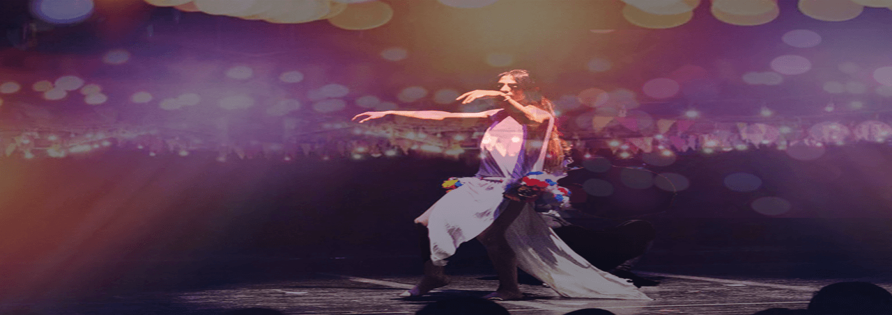 Person dancing on a stage with colourful lights.