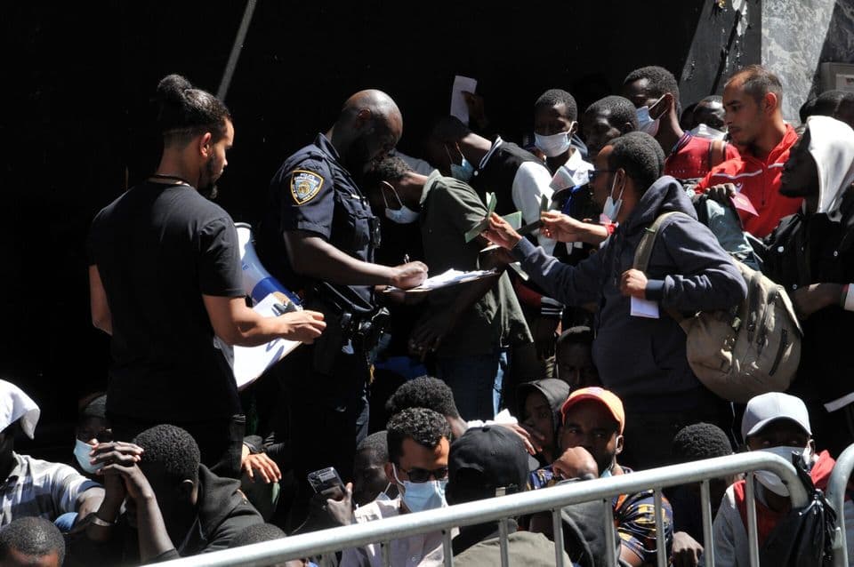 Crowd of people gathered as a police officer writes on a clipboard.