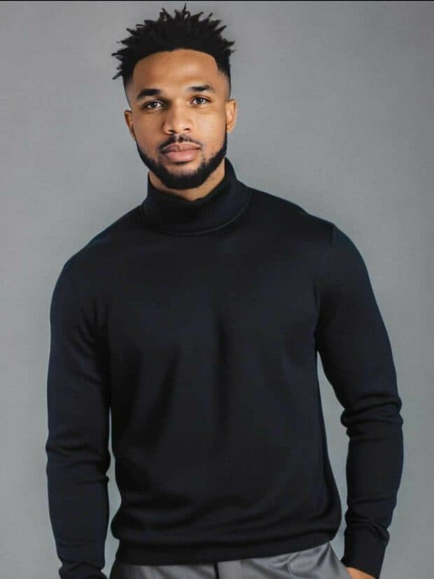 Person in a black turtleneck posing against a gray backdrop.
