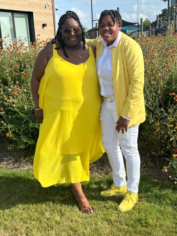 Two people smiling outdoors wearing matching yellow outfits.