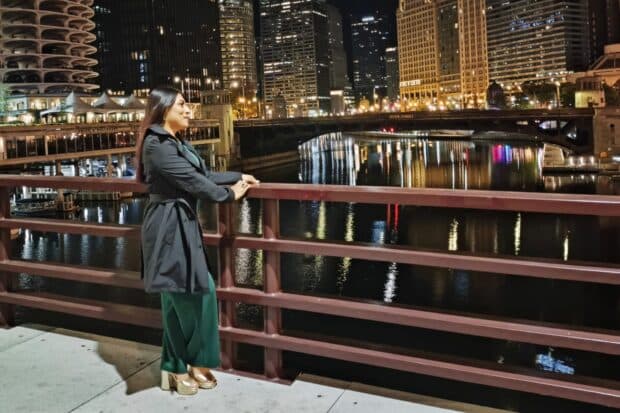 Person standing by a city river at night.