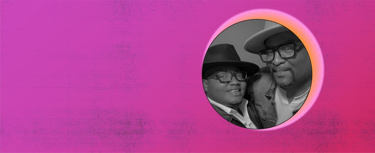 Two people wearing hats and glasses smiling together in a circular portrait with a pink background.